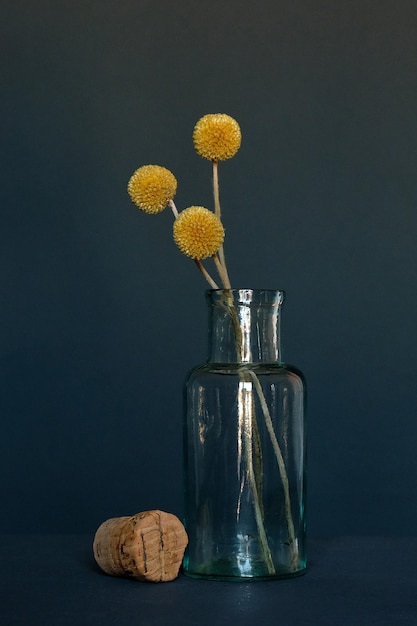 Photo close-up of glass of vase on table against dark background with flowers