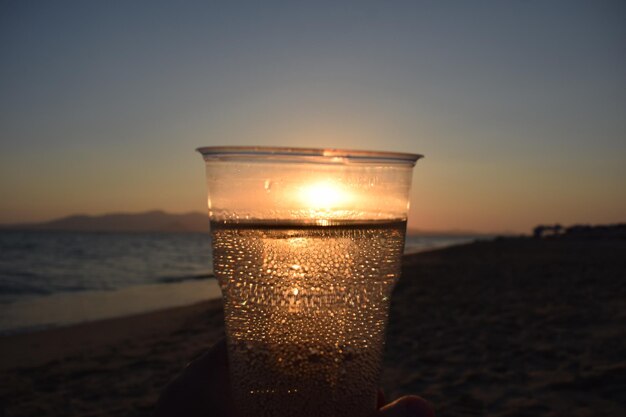 Foto close-up di un bicchiere d'acqua al tramonto