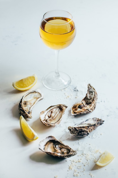 Close-up of a glass of white wine with oysters and lemon on a white background