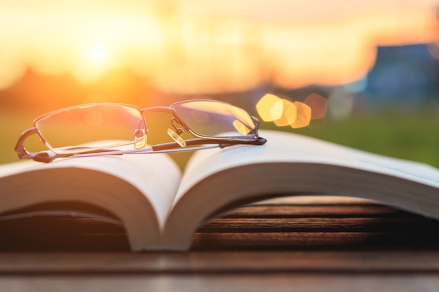 Close up glasses and book on table in sunset time