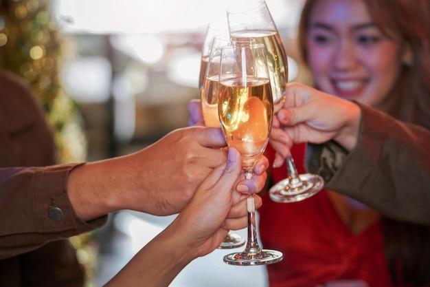 Primo piano di bicchieri di champagne tintinnanti con illuminazione. cena con bevute di champagne. le mani che tengono il vetro trasparente con alcool in lucentezza gialla riflettono.