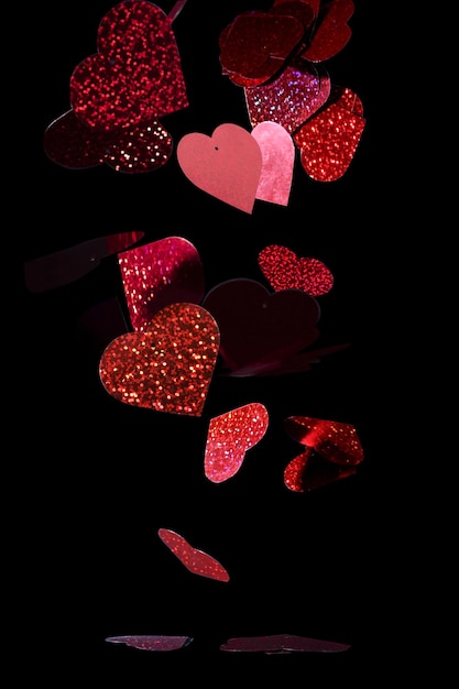 Close-up glittery, rode uitgesneden harten tegen een zwarte achtergrond - Valentijnsdag thema achtergrond