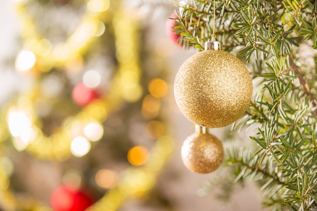 Close-up of gold Christmas ball hanging on Christmas tree.