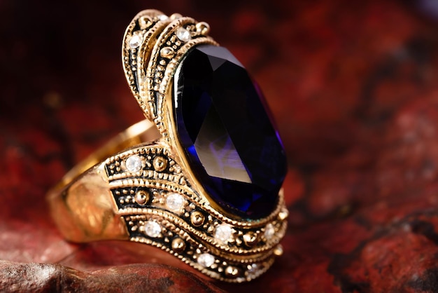 Anello in oro ravvicinato e gemma blu e gioielli dimond su sfondo foglia. anello vintage, gioielli antichi, utilizzati per sfondo moda vintage