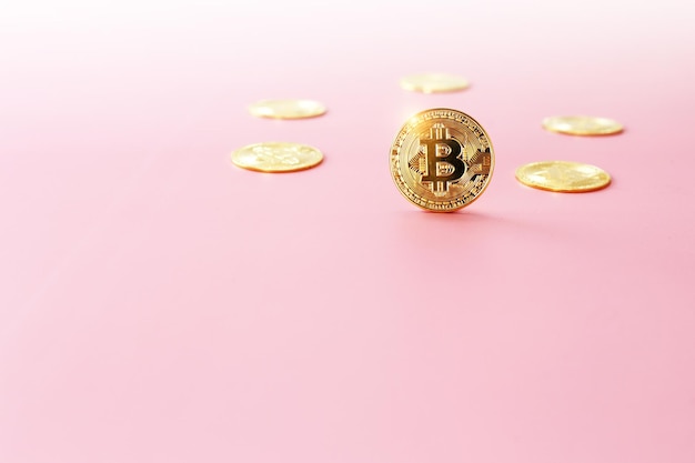 Фото Закрыть золотую монету биткойн на светло-розовом фоне символ криптовалюты блестящая золотая монета биткойн выделяется на фоне других монет с копировальным пространством