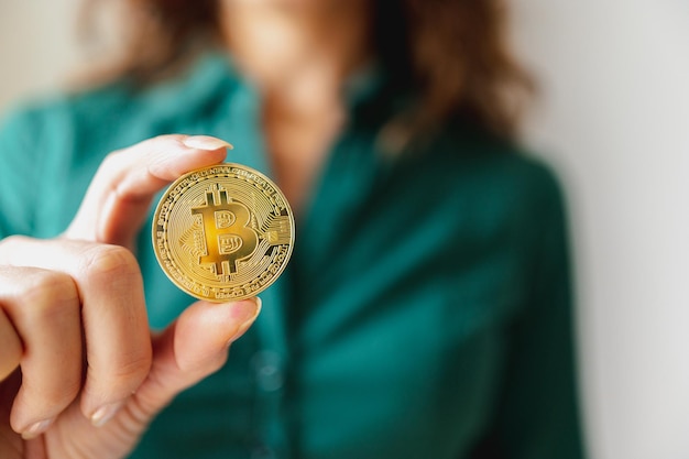 Close-up golden bitcoin. Unrecognizable person showing the coin.