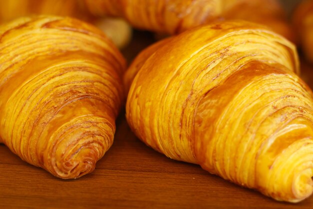 Close up of golden brown croissant on wooden table coffee shop shelf selective focus