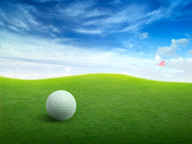 Foto close up palla da golf su campo d'erba verde e bandiera di golf rossa su fairway verde con bellissimo cielo blu