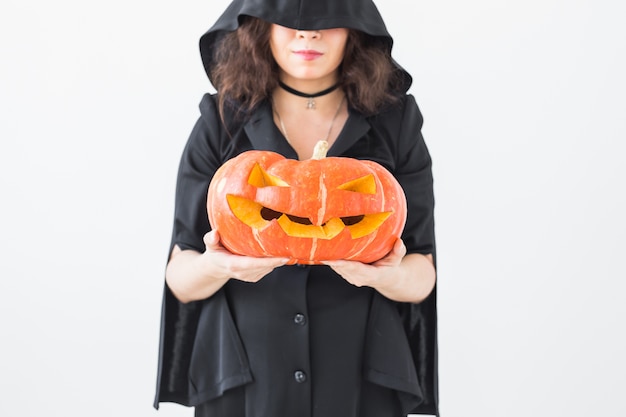 Close up of gothic woman in halloween style clothes with pumpkin in hands