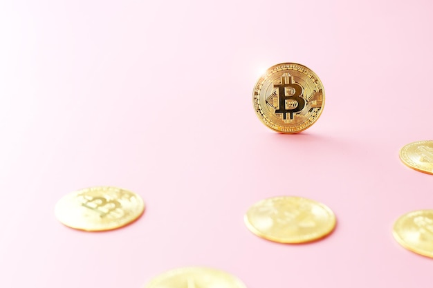 Close-up gouden bitcoin munt op roze achtergrond Cryptocurrency symbool De glanzende bitcoin gouden munt valt op tussen andere munten met kopieerruimte