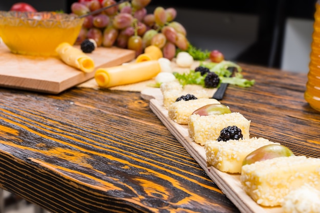 Close Up of Gourmet Fruit and Cheese Board Appetizer on Rustic Wooden Table with Copy Space