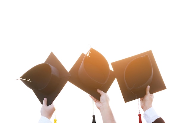 Close up graduate hand hold show hat in background school\
building shot of graduation cap during commencement university\
degree education student success learning concept