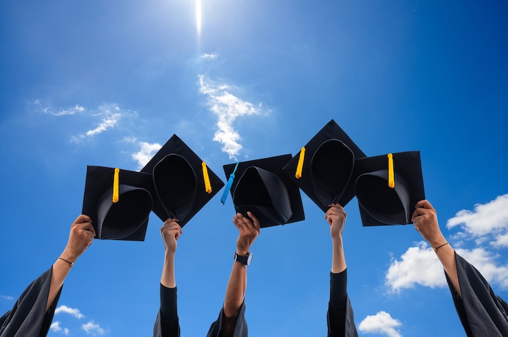 Photo close up of graduates holding hats in hand