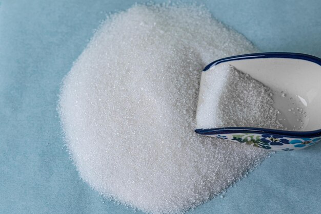 Close-up of granulated sugar in spoon and sugar pile