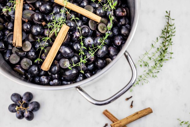 Close-up of grapes with cinnamons and rosemary in colander on table