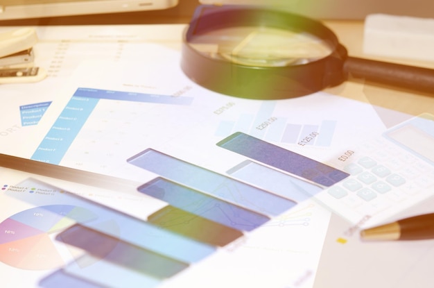 Photo close-up of graph papers and magnifying glass on table