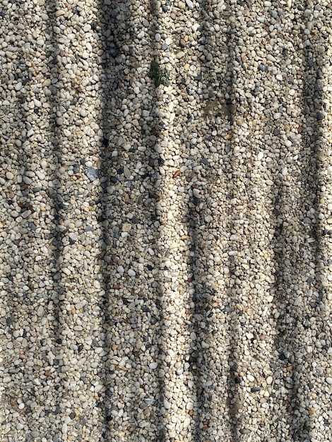 A close up of a gravel texture with a grass patch in the middle.