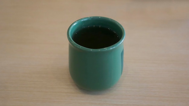 Close up a green ceramic or porcelain mug with tea in it at the table