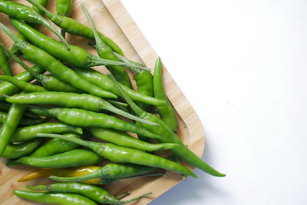 Close up of green chili on a chopping board on white background