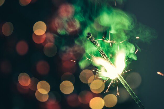 Close-up of green holiday sparkler in the dark