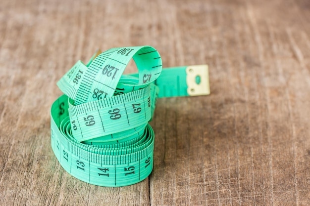 Close up green measuring tape on wooden table