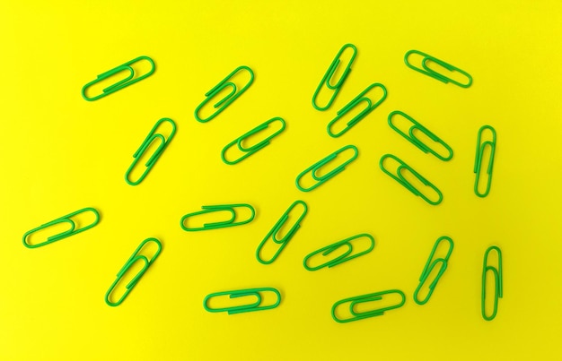 Close-up of green paper clips over yellow background