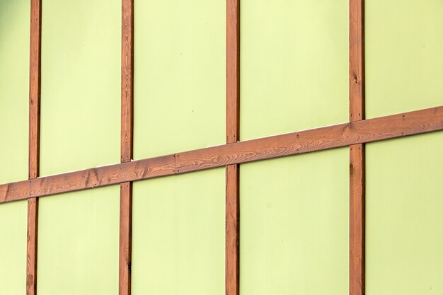 Photo close-up of a green wall of a frame house with brown bars.