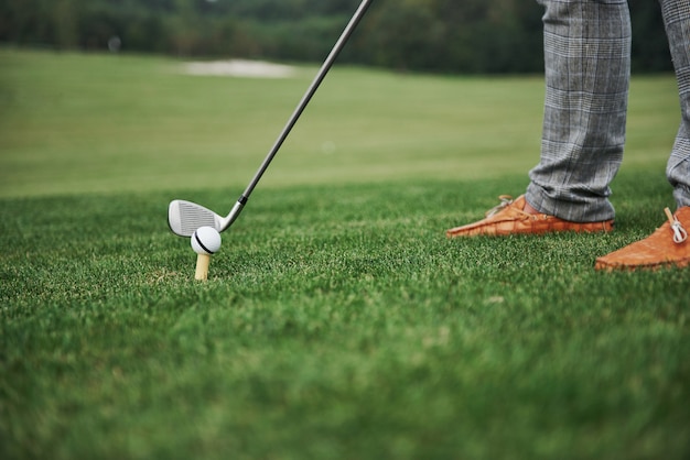 Close-up green zone golf course, white ball and metal stick. The player can only see the legs