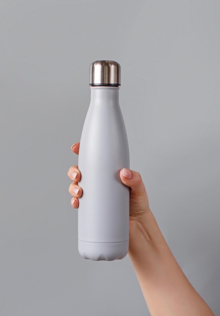 Close-up of grey reusable steel bottle on grey and yellow background