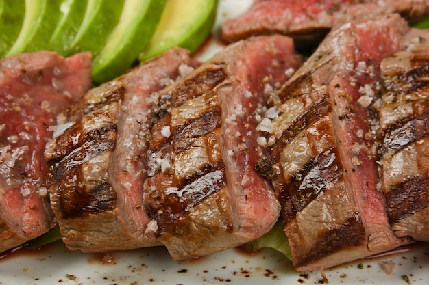 Close up grilled beef tenderloin steak sliced to serve with vegetables, high angle view