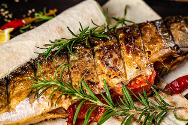 Foto primo piano di pesce sgombro alla griglia con verdure e rosmarino