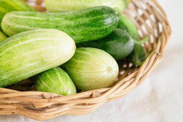 Foto close-up groep verse biologische komkommer of courgette in houten mand op witte tafel