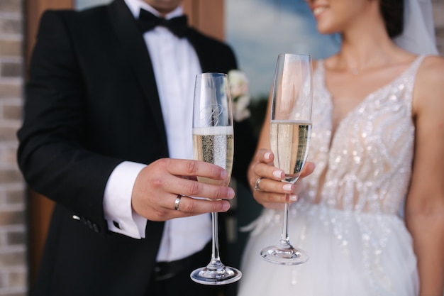 Close-up of groom and bride hold glasses of champagne