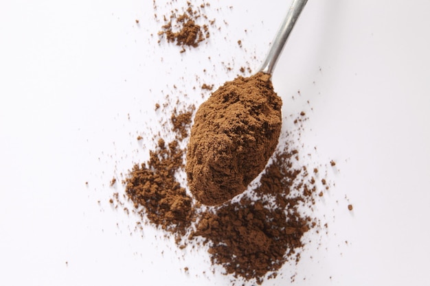 Foto close-up di caffè macinato in cucchiaio su sfondo bianco