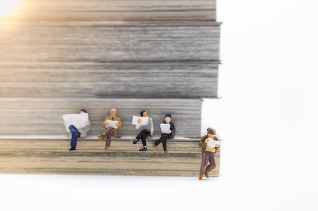 Close up of group of businessman miniature reading with books as.