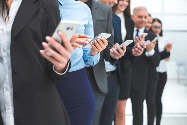 Close up. group of diverse employees with smartphones standing in a row