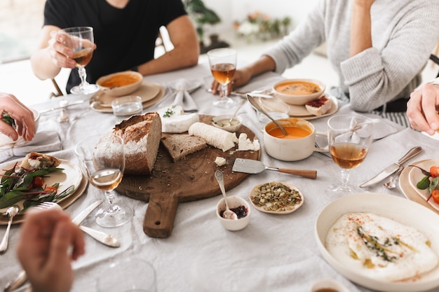 写真 一緒に昼食をとっているおいしい食べ物でいっぱいのテーブルに座っている若者のグループをクローズアップ