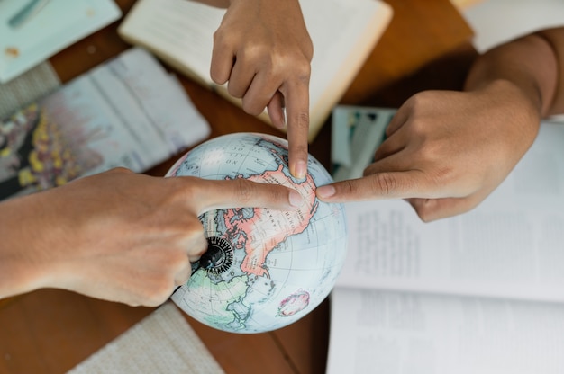 Foto chiuda sul gruppo di persone indicano un dito sul globo