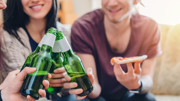 Close up of group young people clinking with beers indoors