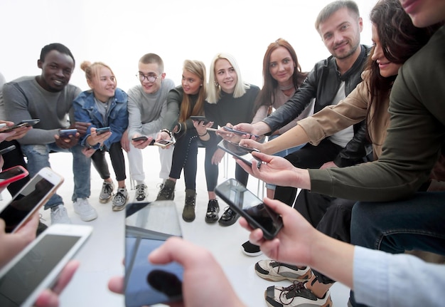 Photo close up groups of young people with smartphones sitting in a circle