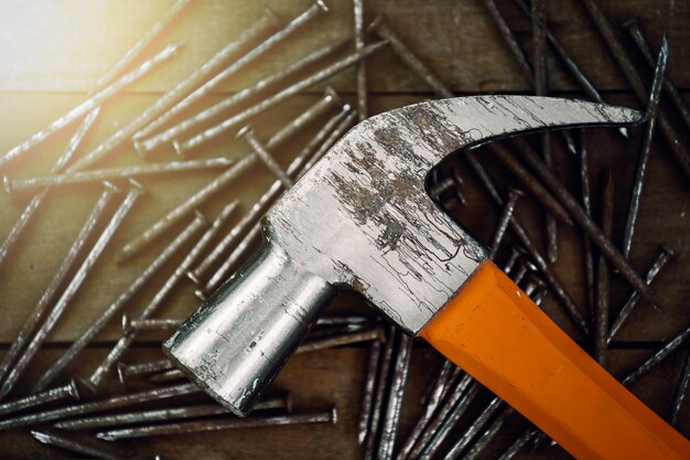 Close-up of grunge hammer on pile nail with wood table