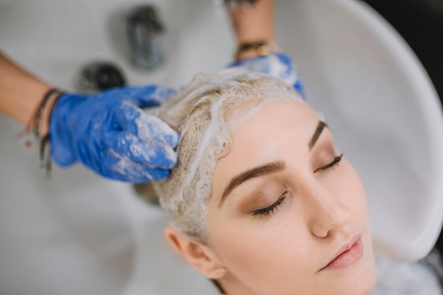 Close-up of hairdresser washing head of client