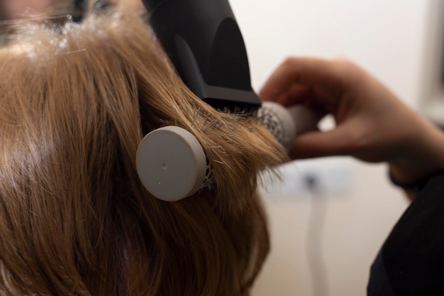 Close up of hairdressers hands drying long blond hair