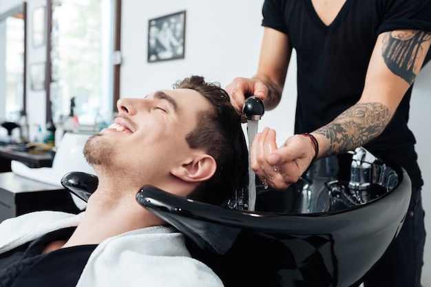 Close-up of a hairstylist washing client&#39;s hair in barber shop