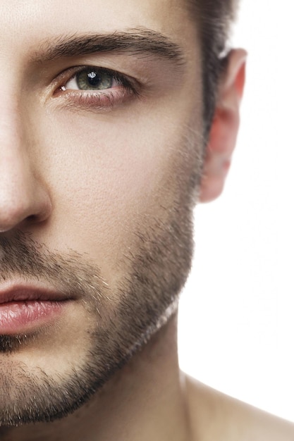 Close-up of half of male face. Men's beauty. Young handsome man with smooth skin on white background.