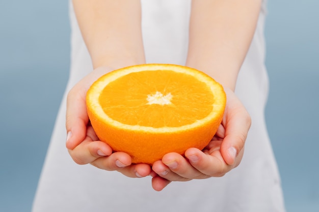 닫기, 파란색에 고립 된 여자의 손에 절반 오렌지