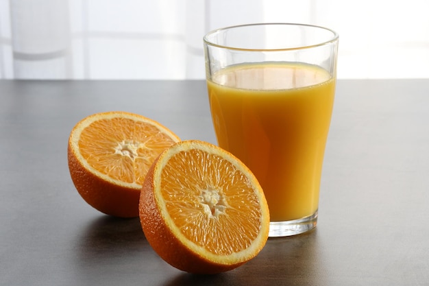 Foto close-up di arance tagliate a metà con il succo in bicchiere su tavola