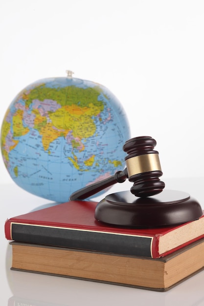 Photo close-up of hammer and gavel with books and mortarboard against white background