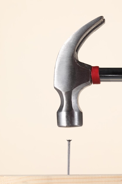 close-up of hammer over nail on wood against wall