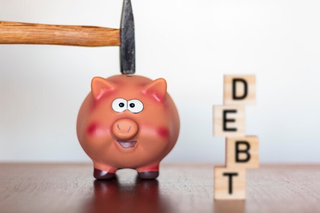 Photo close-up of hammer on piggy bank on table